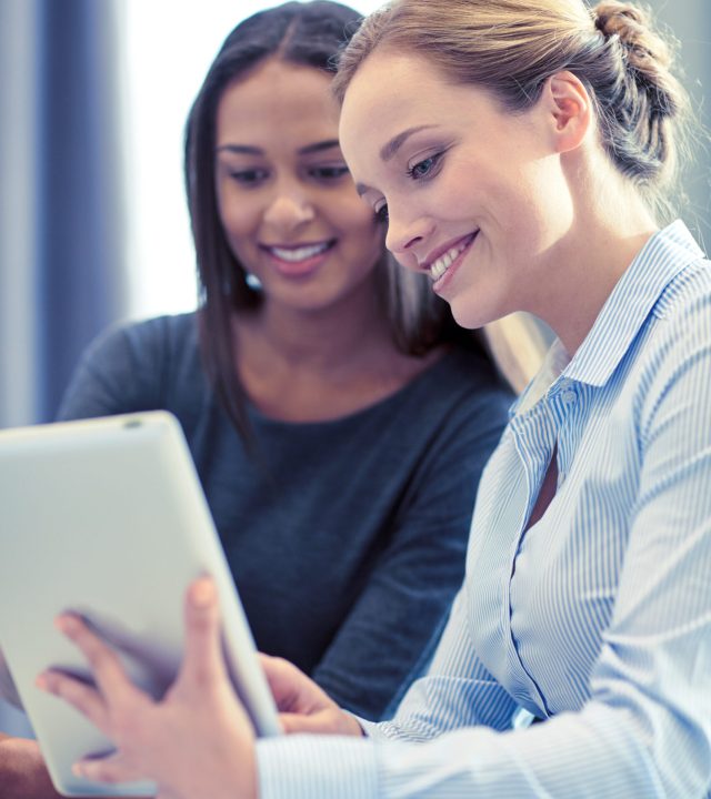 business, people and technology concept - smiling businesswomen with tablet pc computer meeting in office
